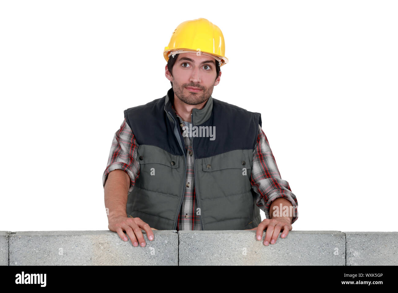 craftsman leaning on a stone block wall Stock Photo