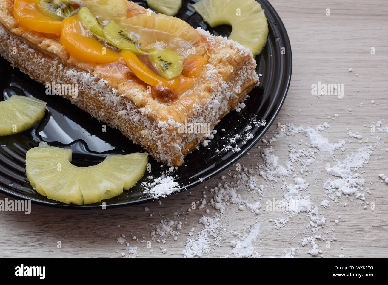 Dessert of puff pastry and fruits on a plate and sugar glass on the table Stock Photo