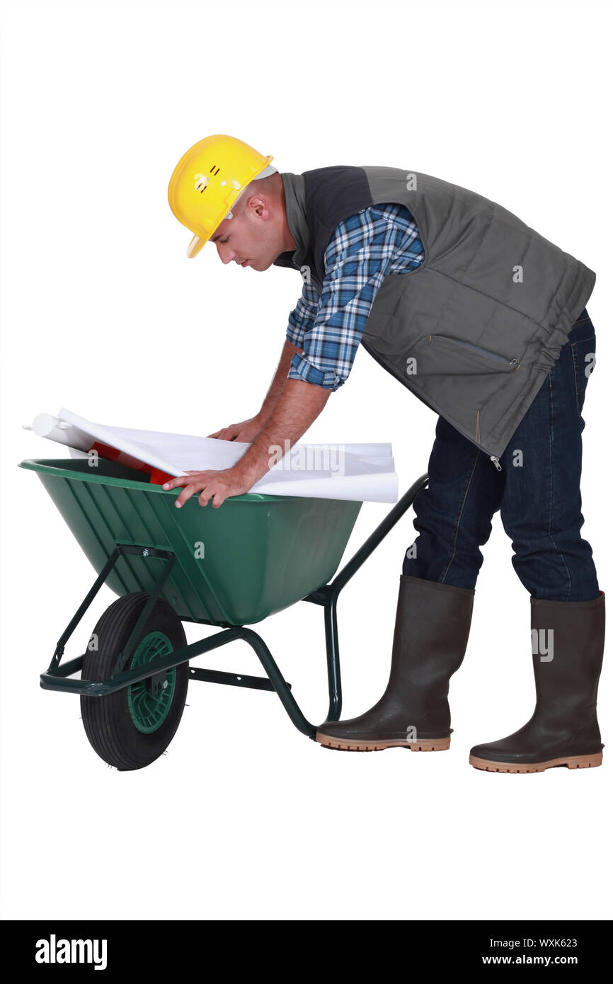 Tradesman looking at a blueprint while leaning over a wheelbarrow Stock ...