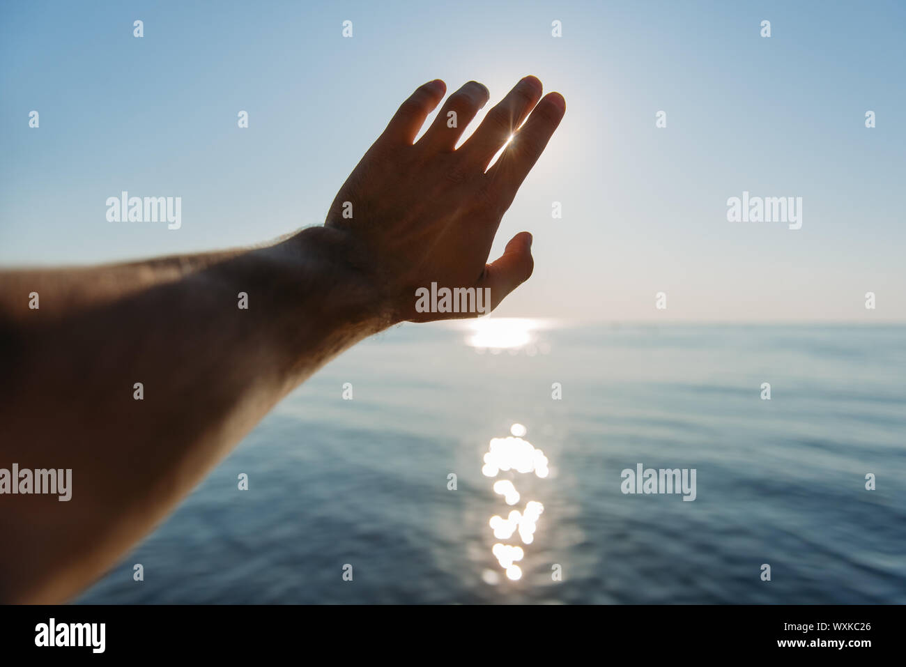 Man's hand reaching for the sun Stock Photo