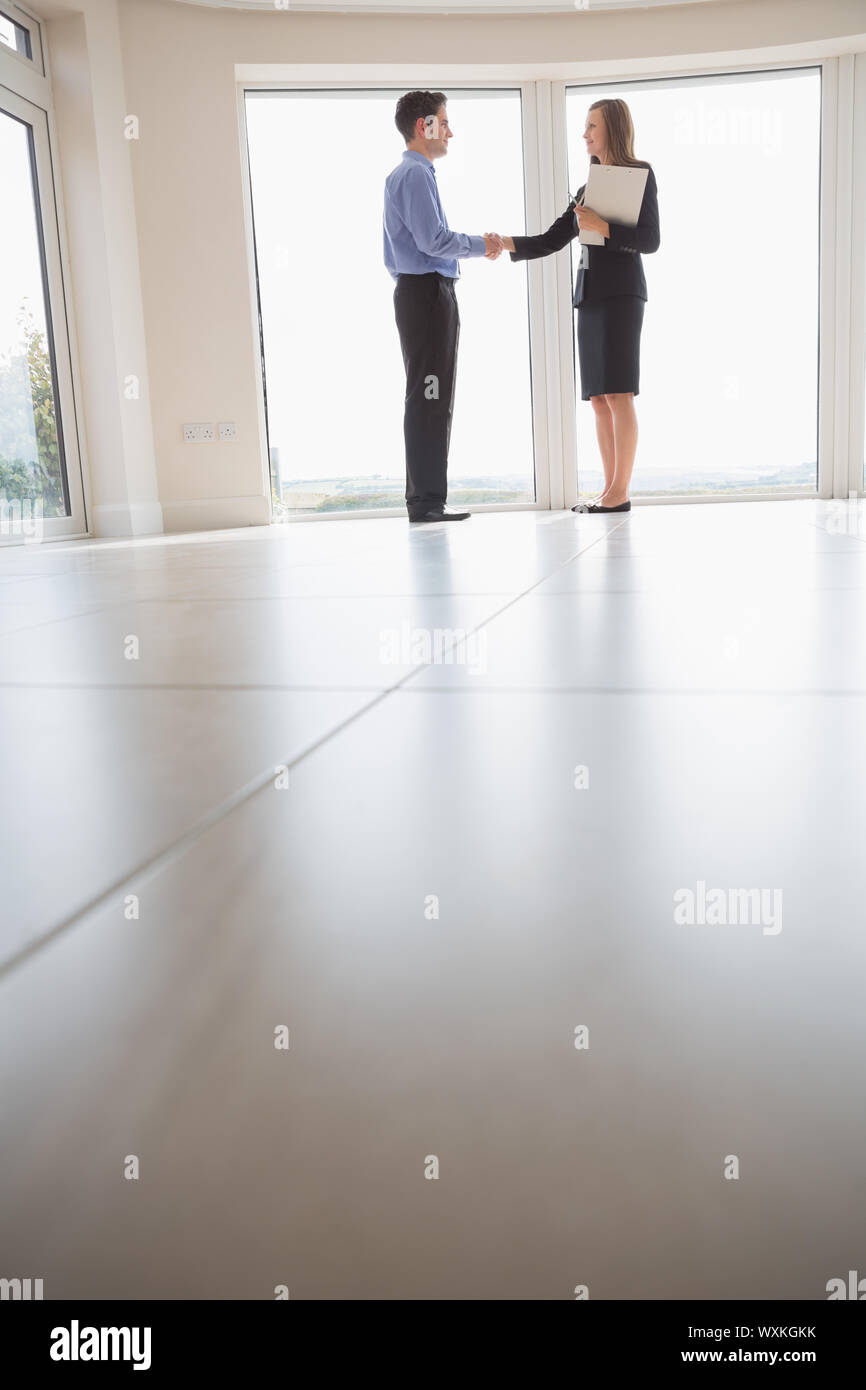 Estate agent and man shaking hands in new house Stock Photo - Alamy