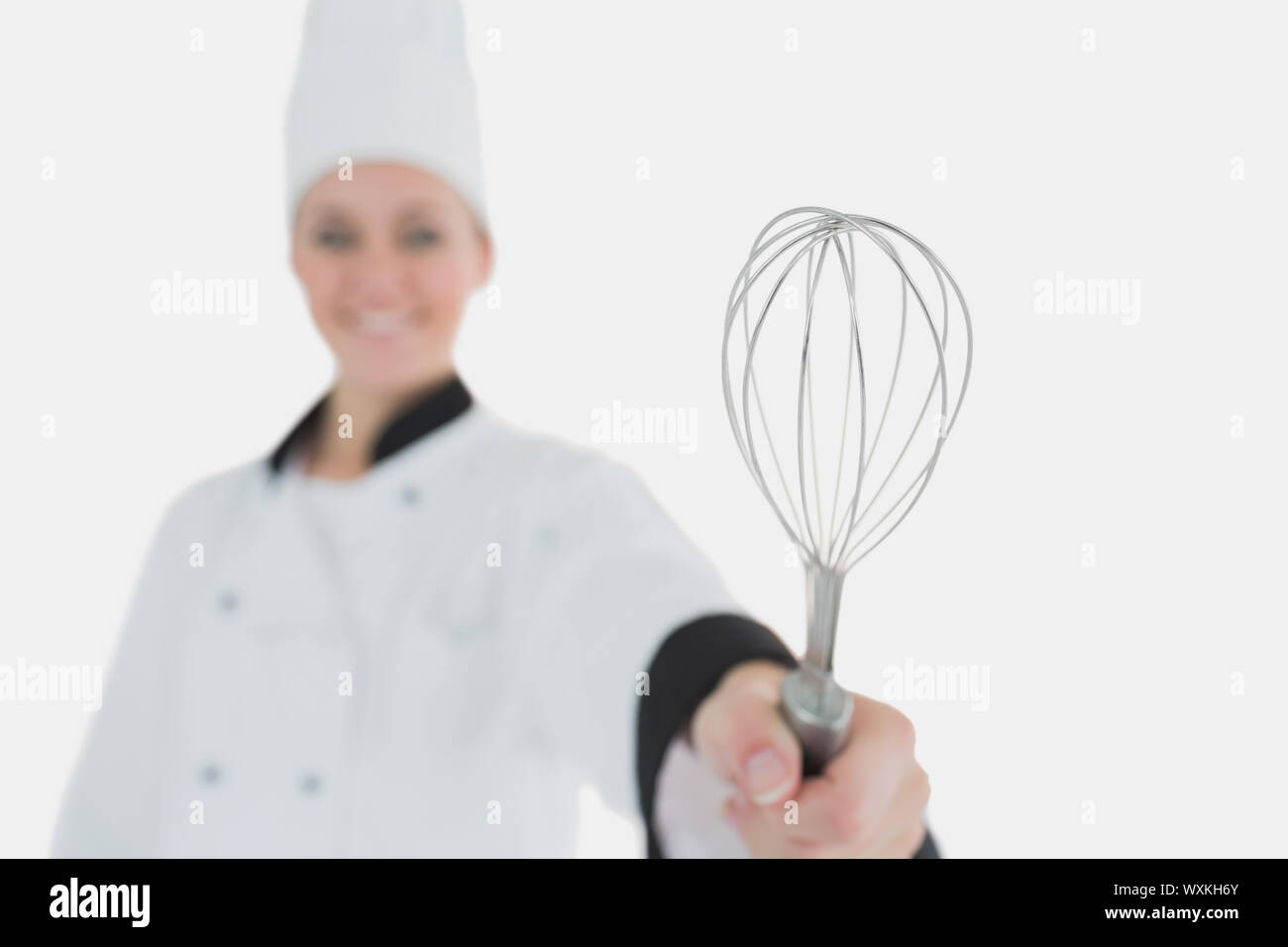 Female chef holding wire wisk against white background Stock Photo - Alamy