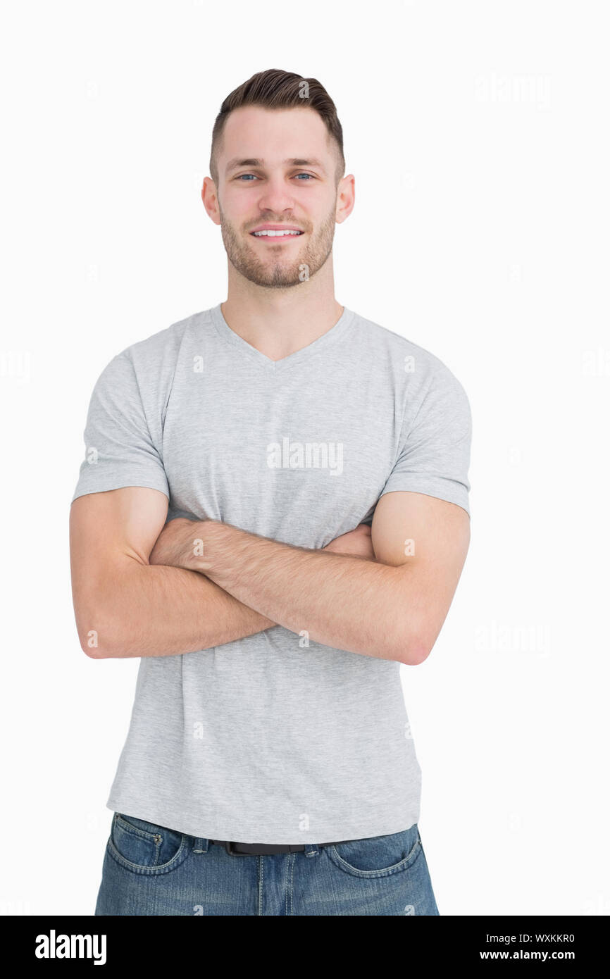 Portrait of casual young man standing with arms crossed over white ...