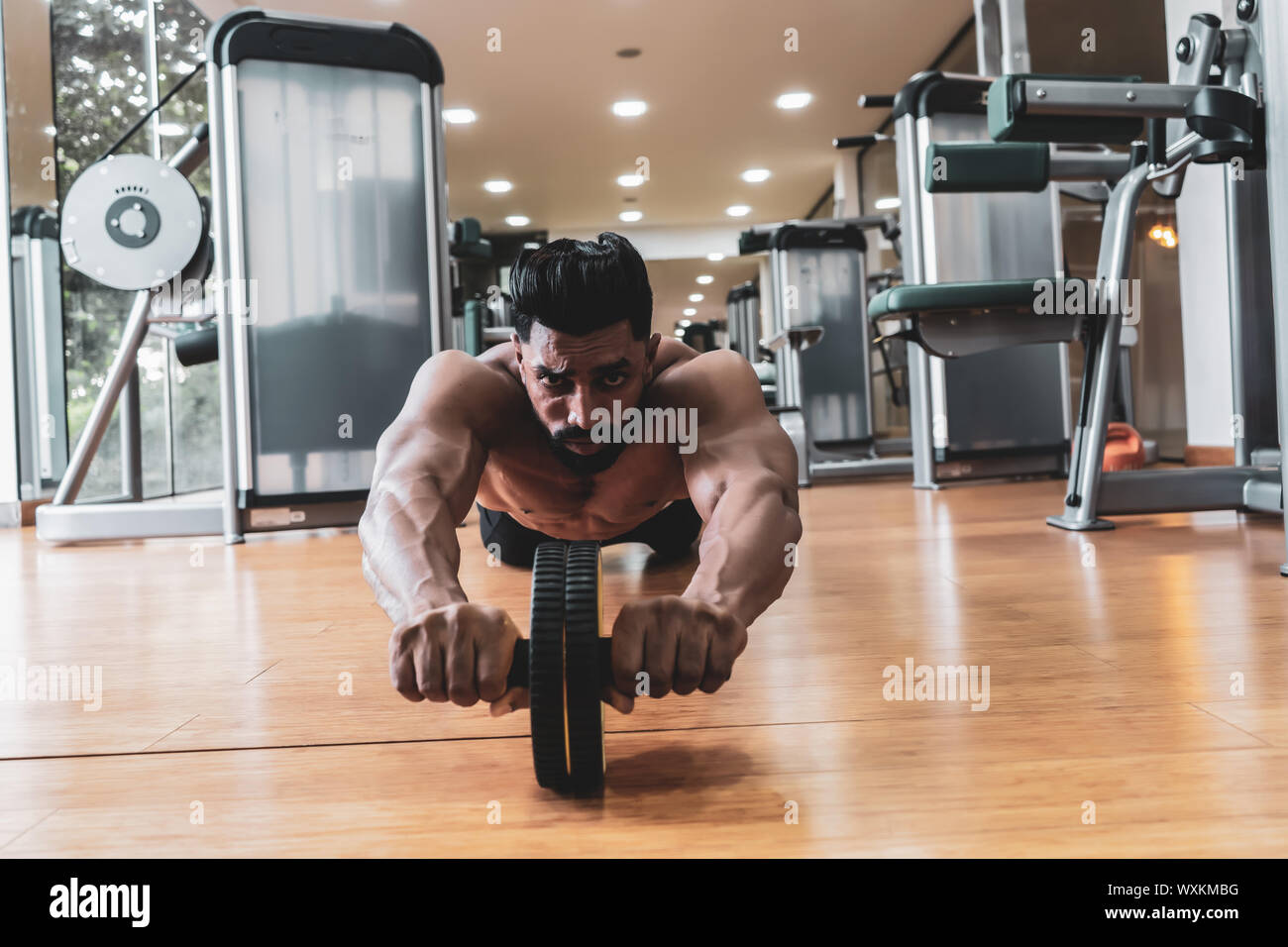 Athlete sporty man doing exercise with abs roller wheel to strengthen