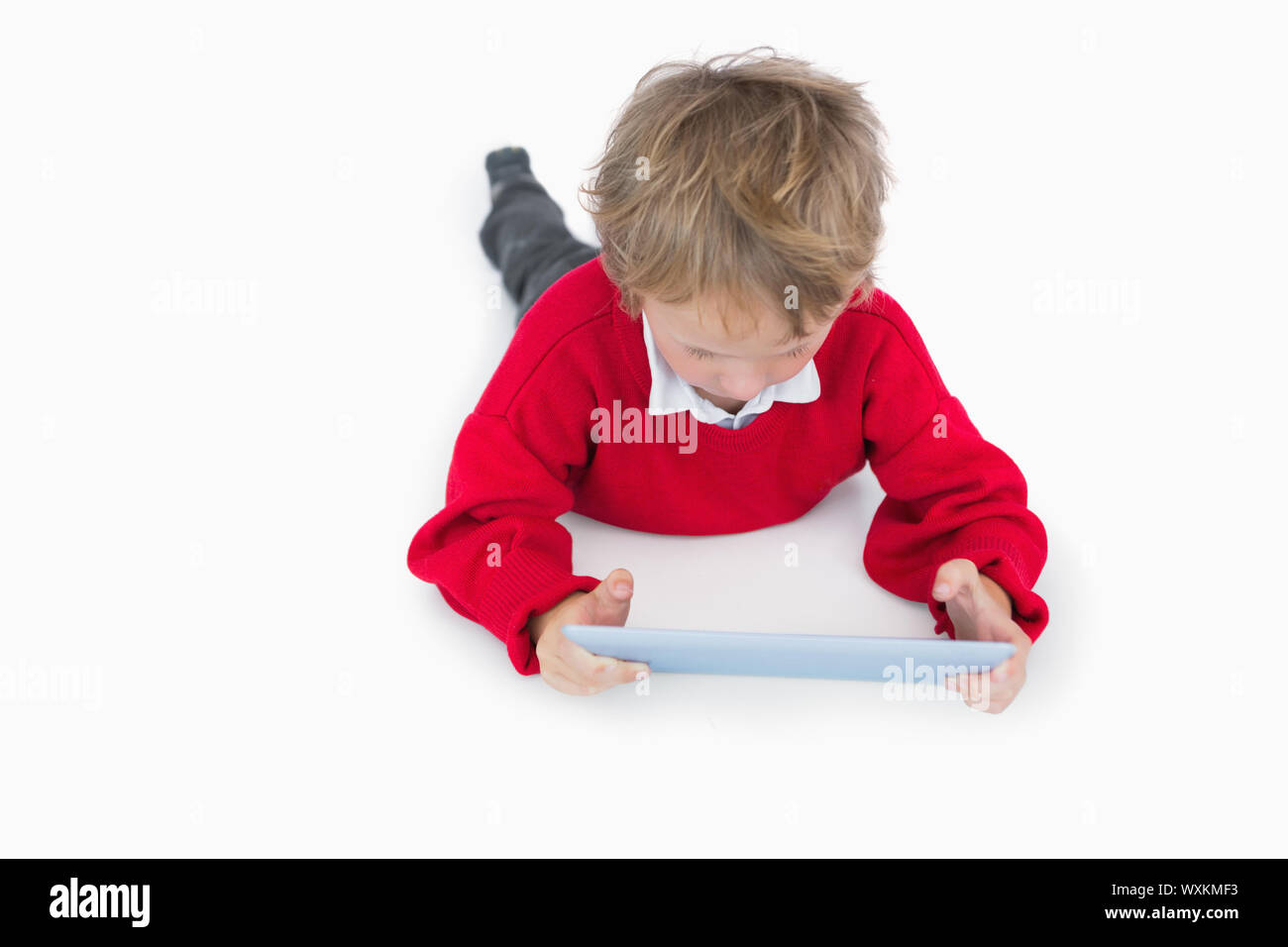Little boy lying on floor and using digital tablet over white ...