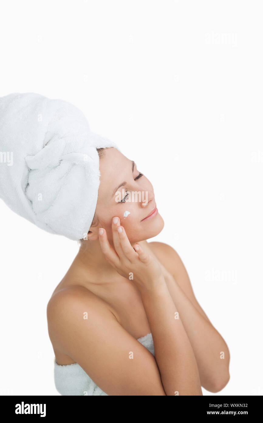 https://c8.alamy.com/comp/WXKN32/young-woman-wrapped-in-towel-applying-cream-on-face-over-white-background-WXKN32.jpg