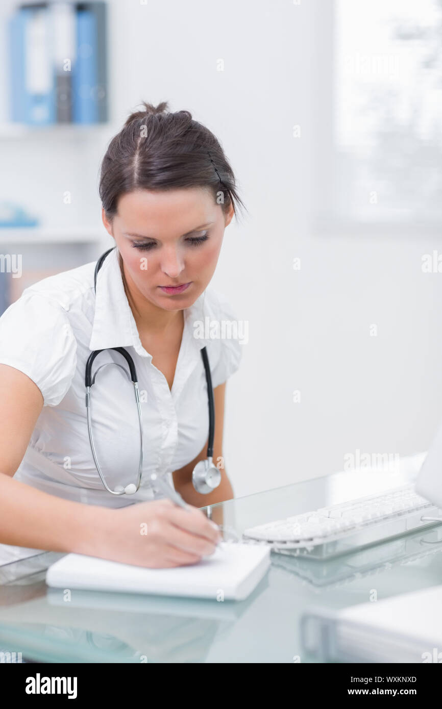 Female doctor writing a prescription at desk in clinic Stock Photo - Alamy