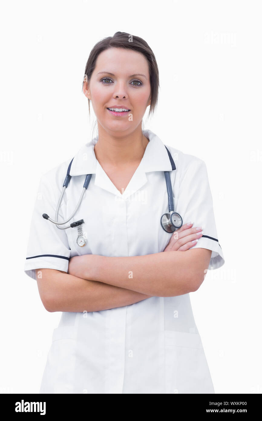 Portrait of smiling female nurse standing with arms crossed over white ...