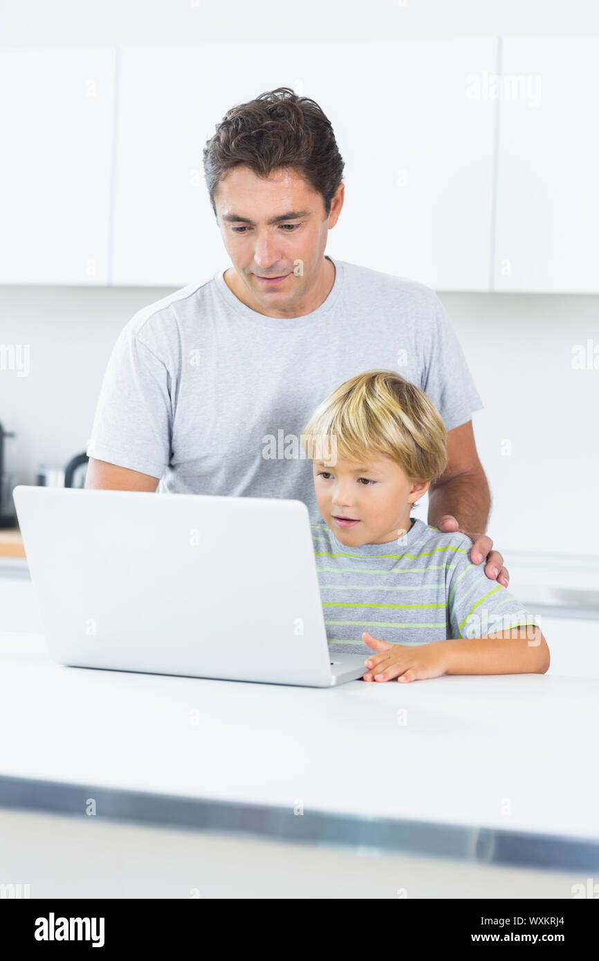 Father and son using laptop in kitchen Stock Photo