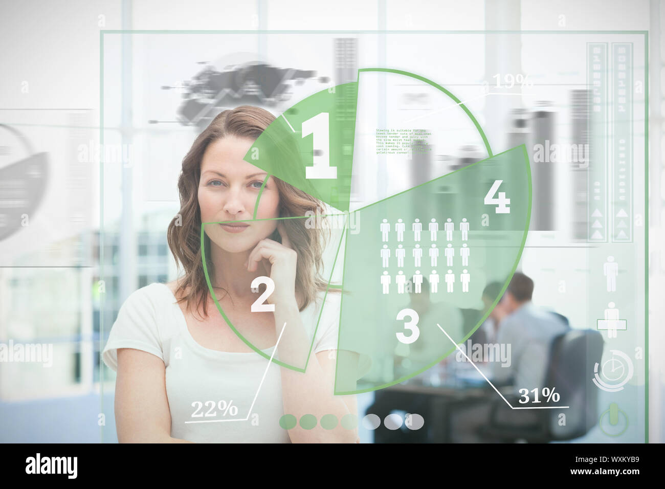 Blonde businesswoman using green pie chart interface with colleagues behind her Stock Photo