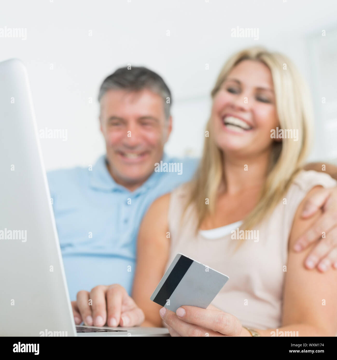 Happy couple using laptop on the sofa to chop online Stock Photo - Alamy