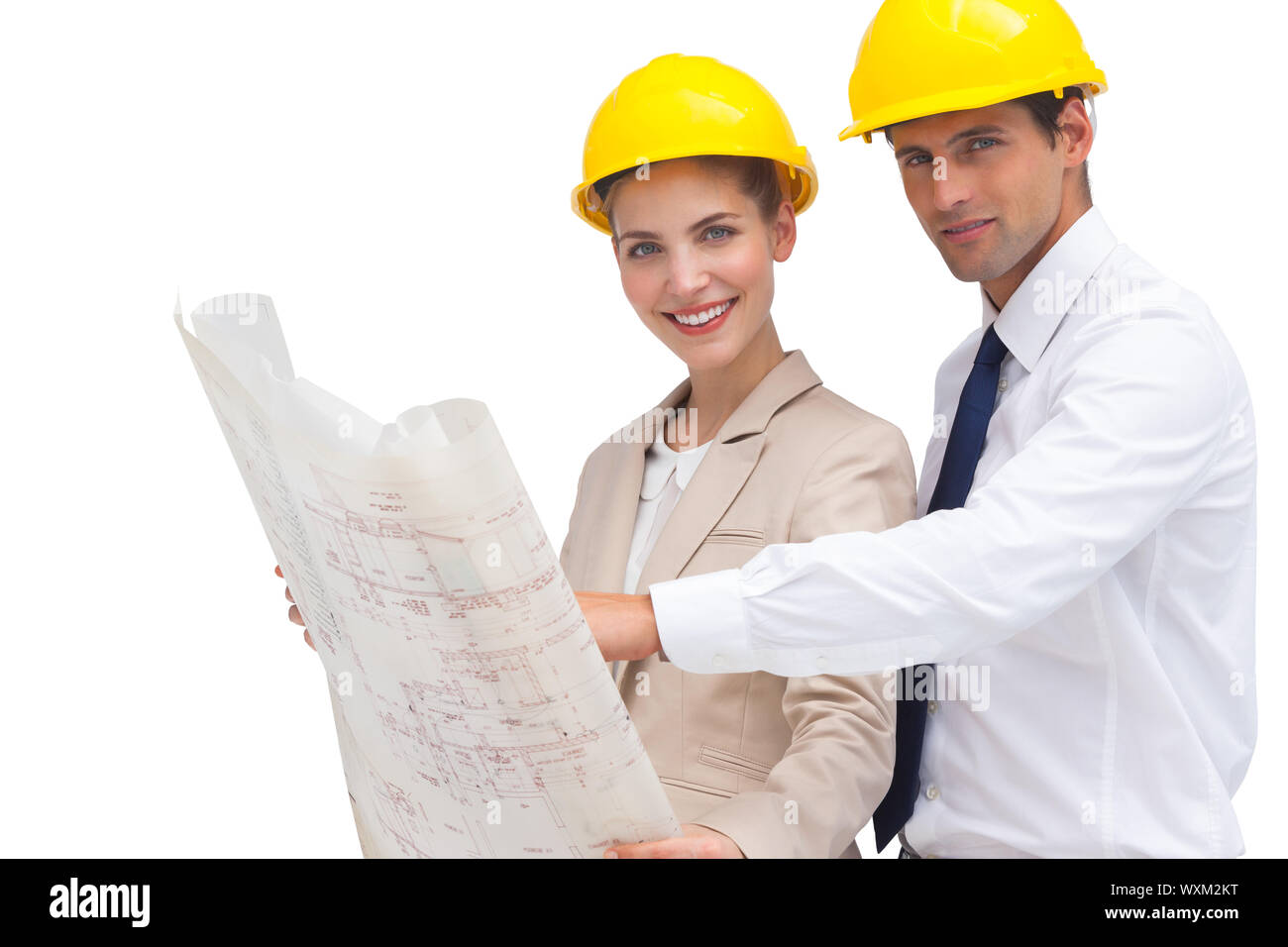 Two architects with construction plan and yellow helmets looking at the camera Stock Photo