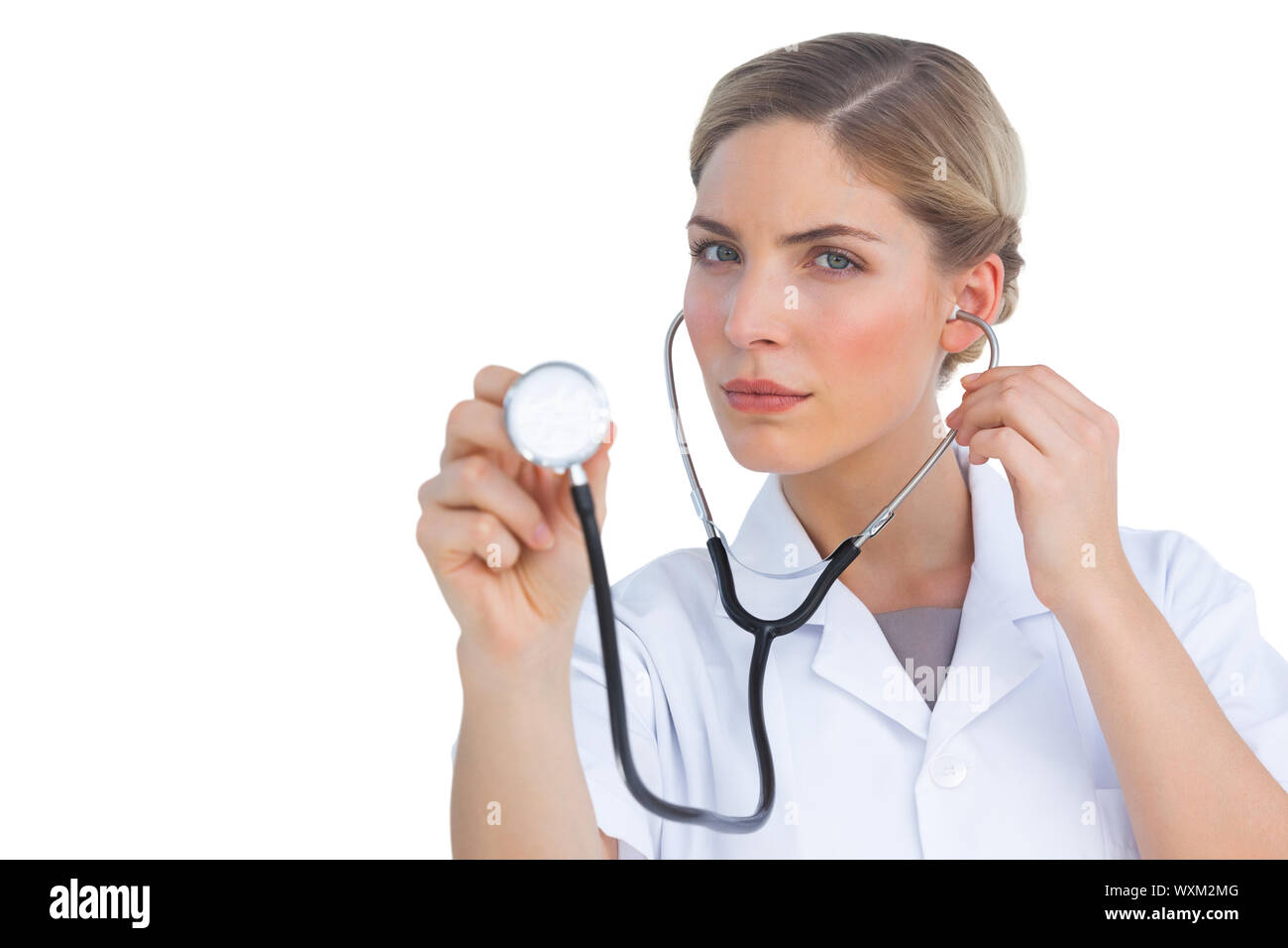 Serious nurse listening with stethoscope and looking at the camera ...