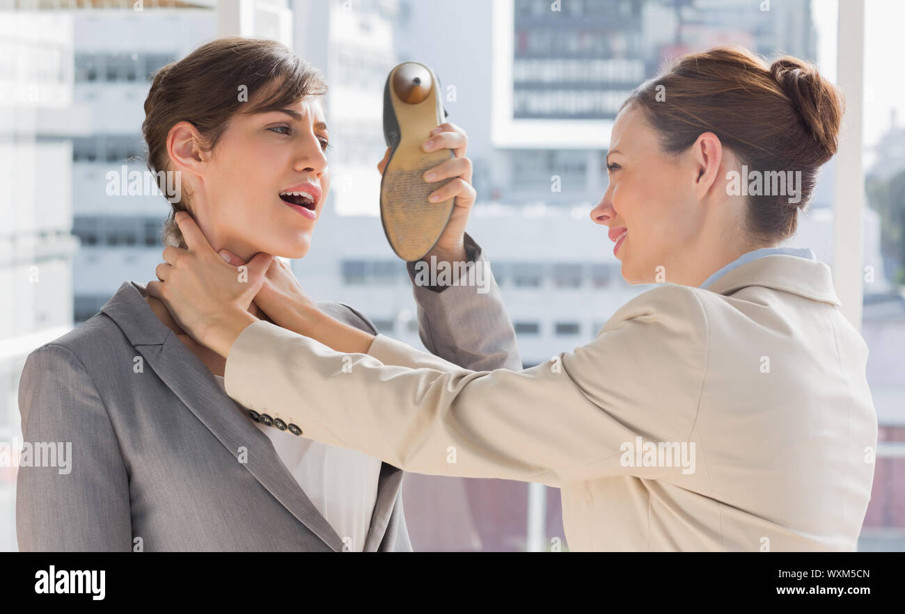 Businesswoman defending herself from her colleague strangling her in a bright office Stock Photo