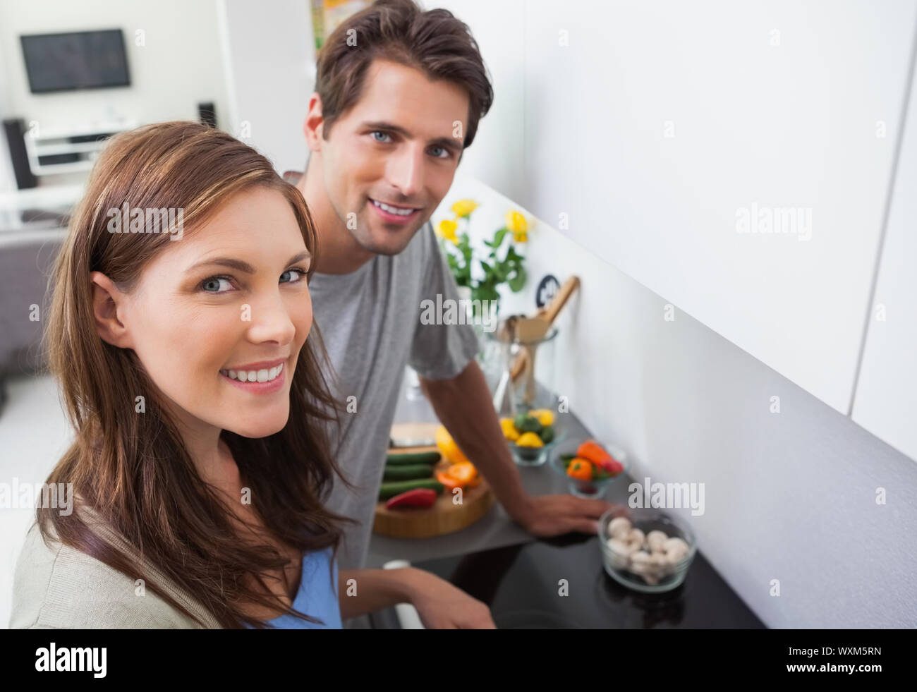Couple cooking and smiling at camera Stock Photo - Alamy