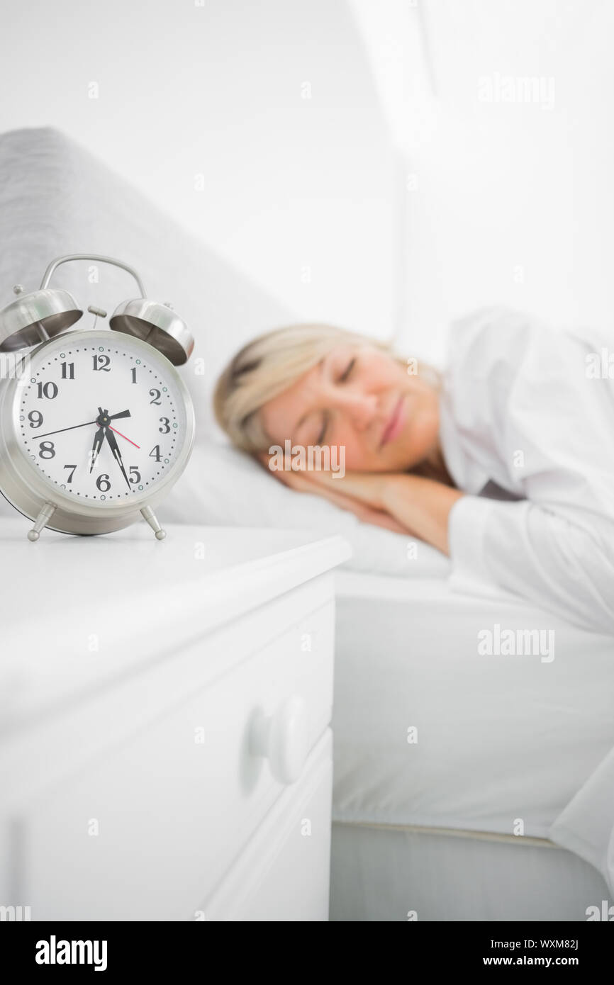 Blonde woman asleep in bed before her alarm clock goes off Stock Photo