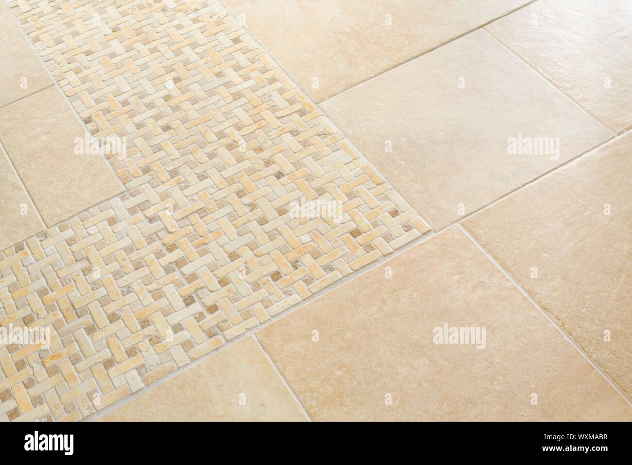 Floor tiles in a home interior with neutral sandstone  porcelain tiles and a mosaic accent Stock Photo