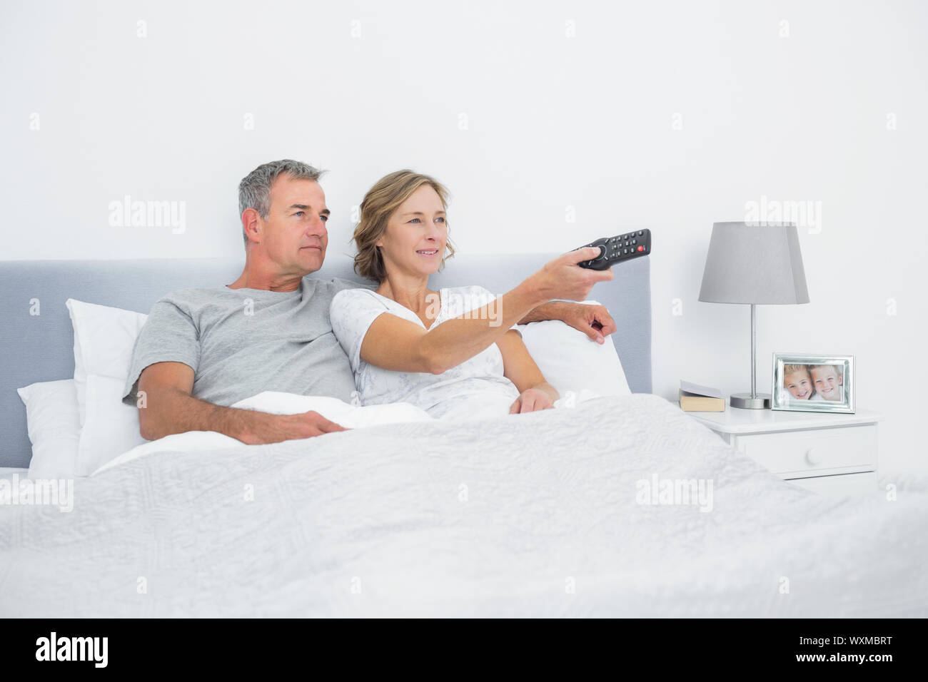 Happy couple watching tv in bed at home in bedroom Stock Photo Alamy