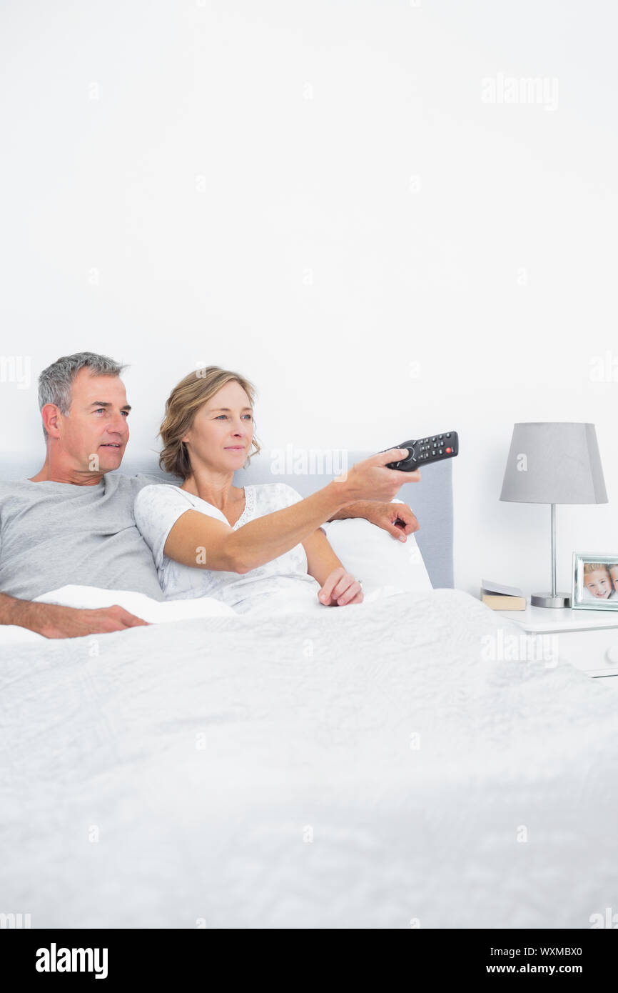 Content couple watching tv in bed at home in bedroom Stock Photo Alamy