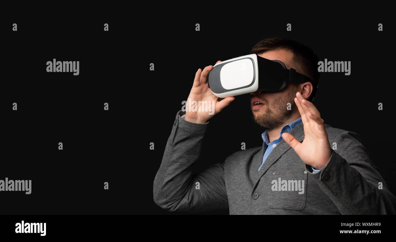 Shocked businessman wearing VR headset, touching virtual object Stock Photo
