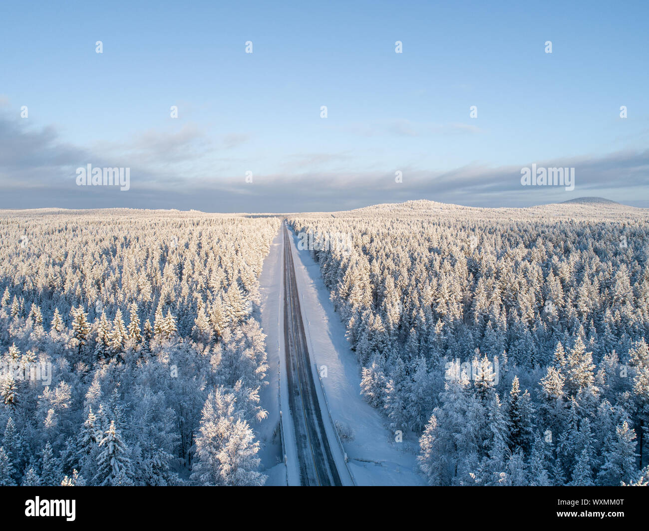 Aerial view of a road in the middle of vast taiga forest at winter in Finland Stock Photo