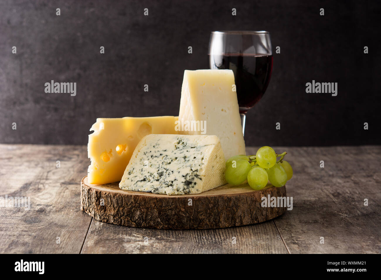 Assortment of cheeses and wine on wooden table. Stock Photo