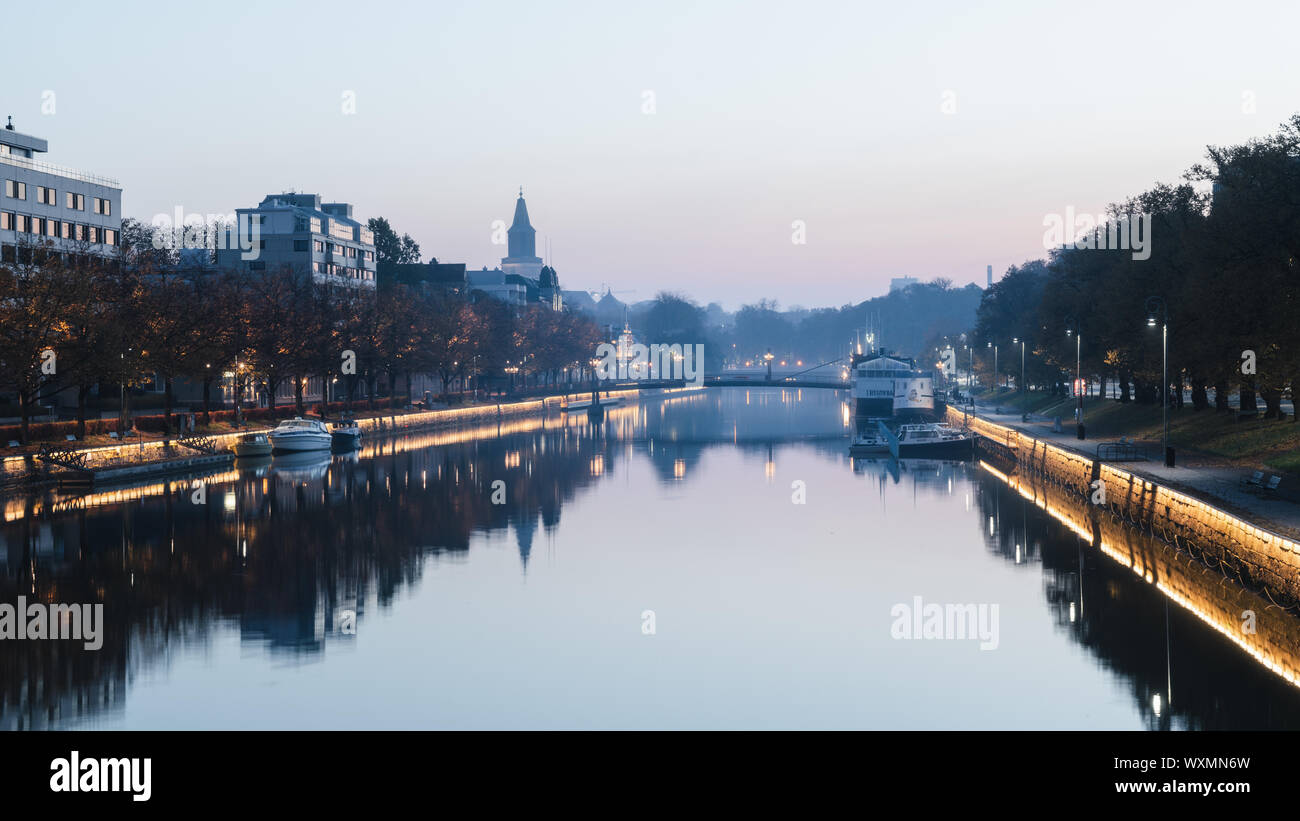 Turku, Finland - 14/10/2018: Calm Aurajoki River with tower of Turku Cathedral in the background at hazy autumn morning in Turku, Finland Stock Photo