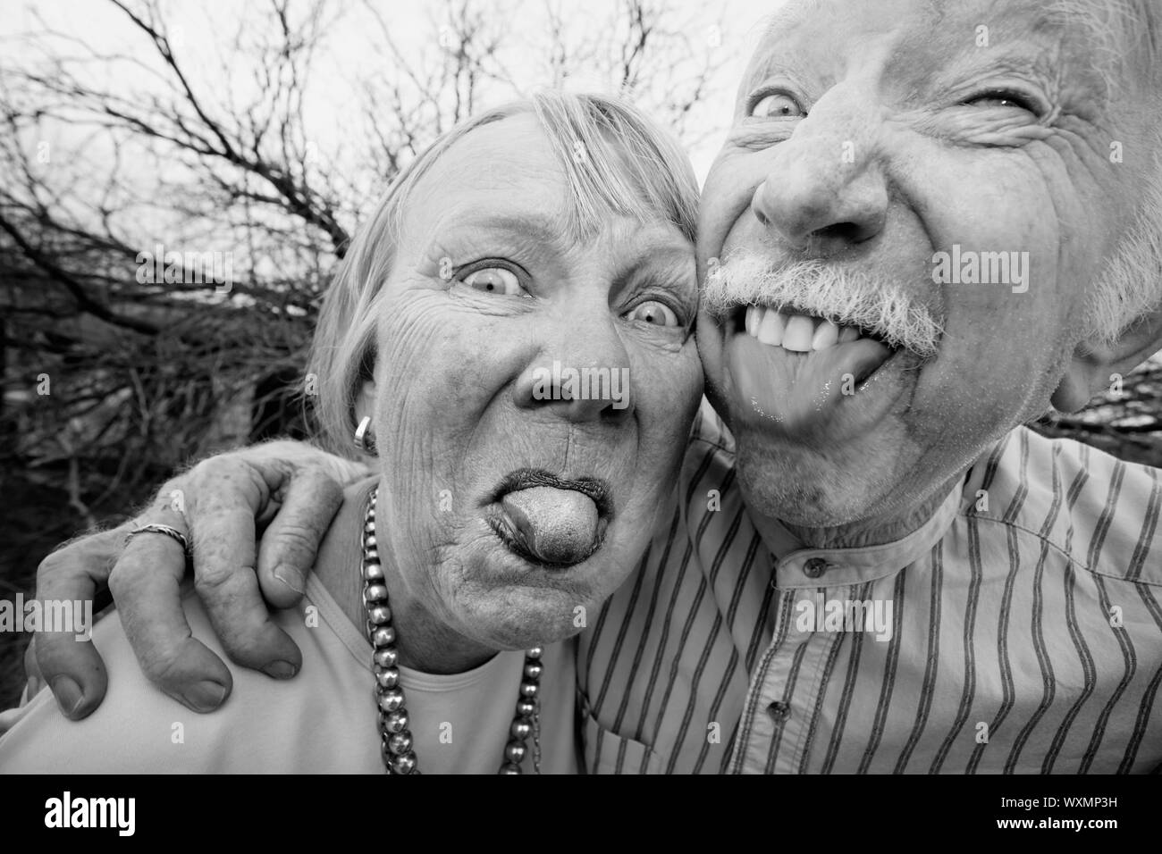 Closeup portrait of crazy elderly couple outdoors sticking out tongues Stock Photo