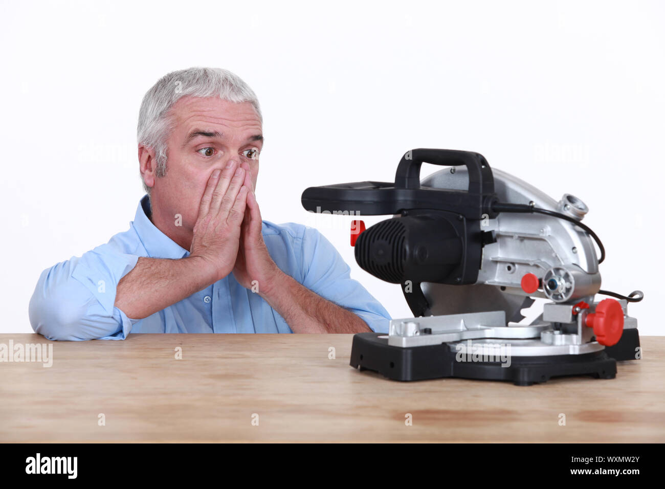 Mature looking at his circular saw with disarray Stock Photo