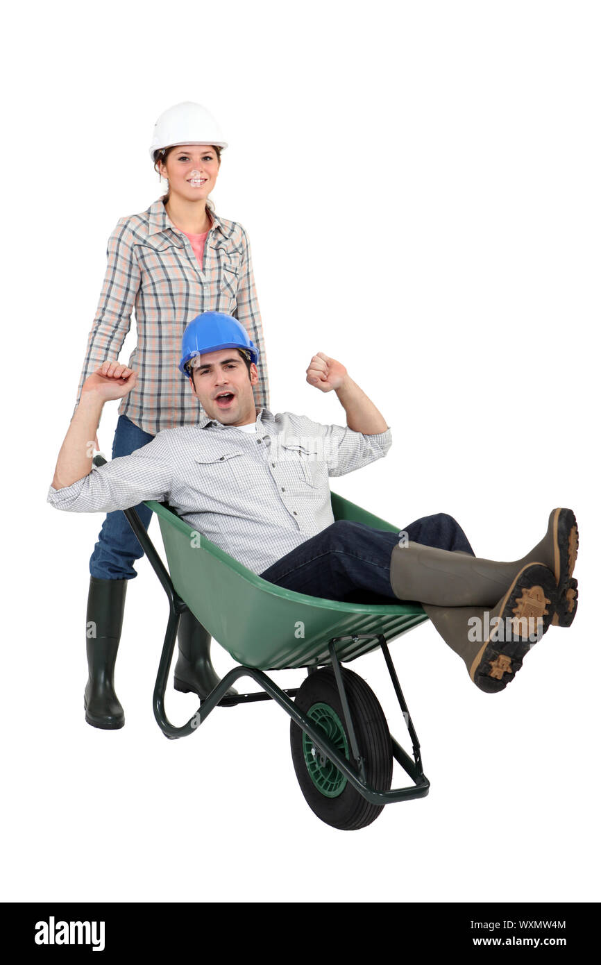 Woman pushing her colleague in a wheelbarrow Stock Photo - Alamy