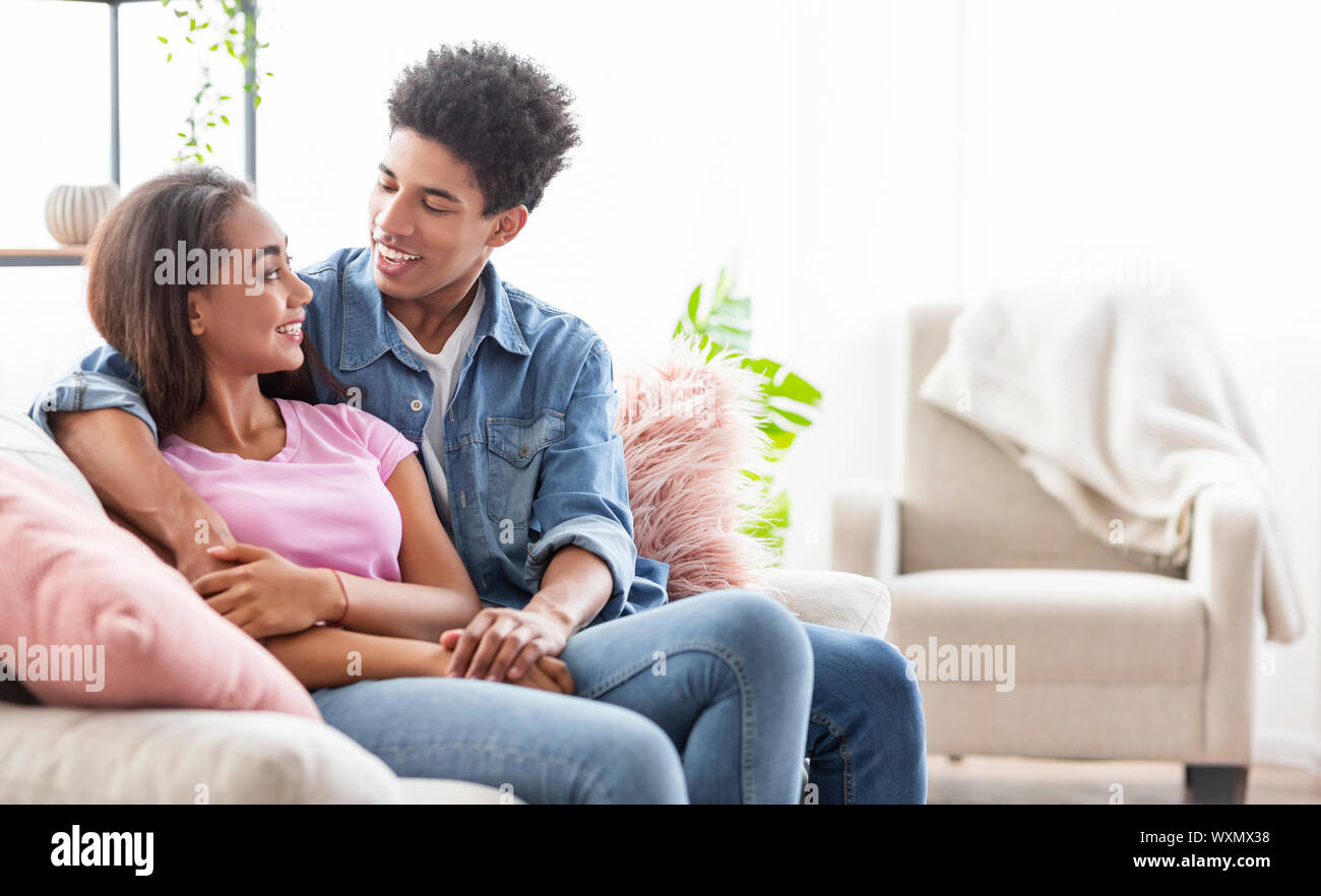 Romantic couple sitting on couch at home, embracing each other Stock Photo