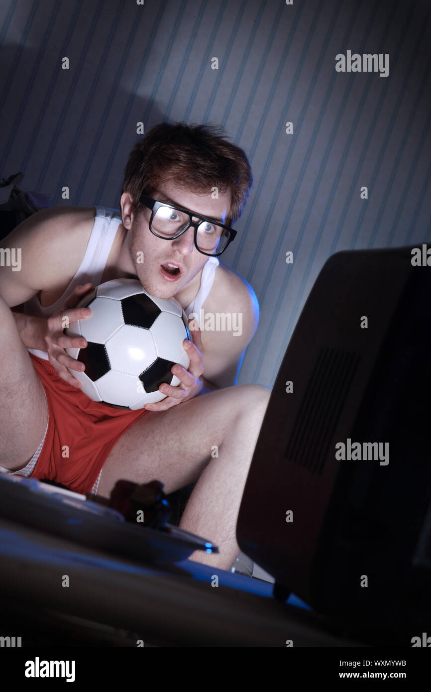 Young man soccer fanatic getting really into the soccer game on television Stock Photo