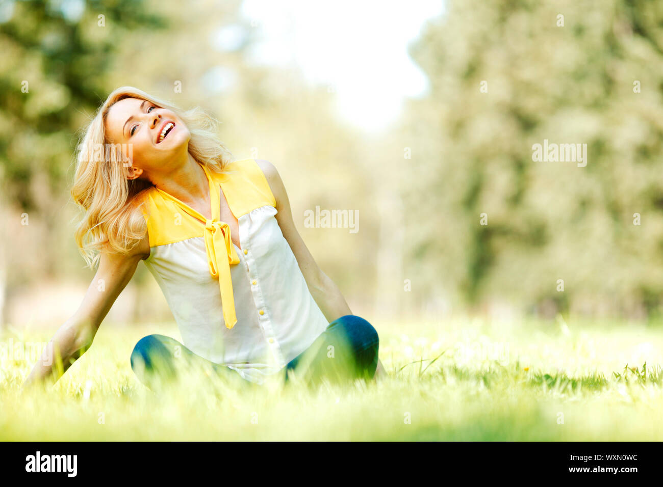 Beautiful happy young woman sitting on grass Stock Photo - Alamy