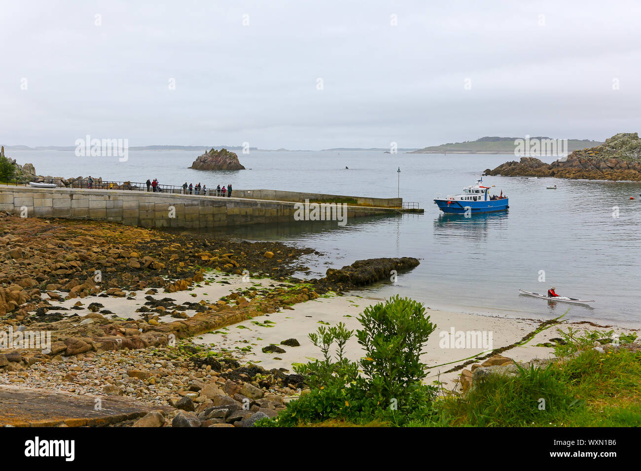 A boat called Firethorn arriving, and tourists waiting to board, at the quay at St. Agnes Island, Isles of Scilly, Cornwall, England, UK Stock Photo