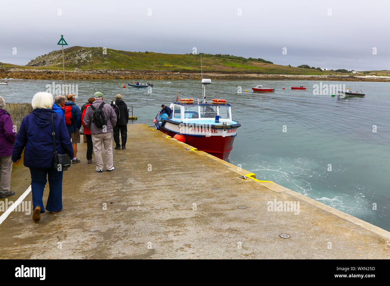 A boat called Surprise arriving, and tourists waiting to board, at the quay St. Agnes Island, Isles of Scilly, Cornwall, England, UK Stock Photo