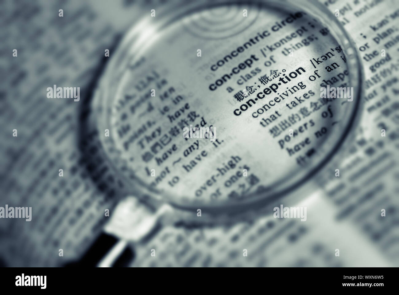 Focus on conception word with magnifier in book. Stock Photo