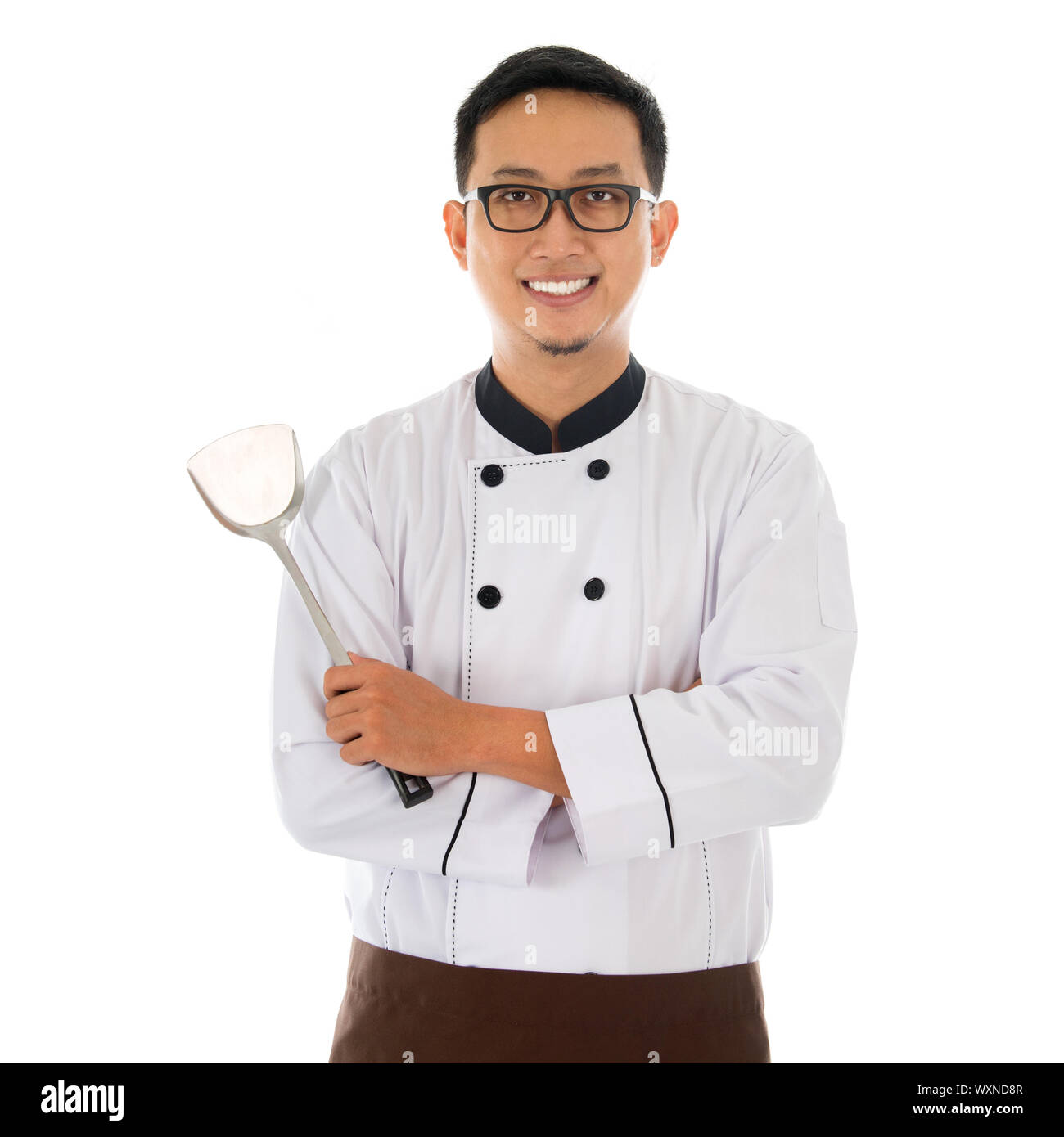Portrait of Asian chef holding spatula, smiling and standing isolated on white background. Stock Photo
