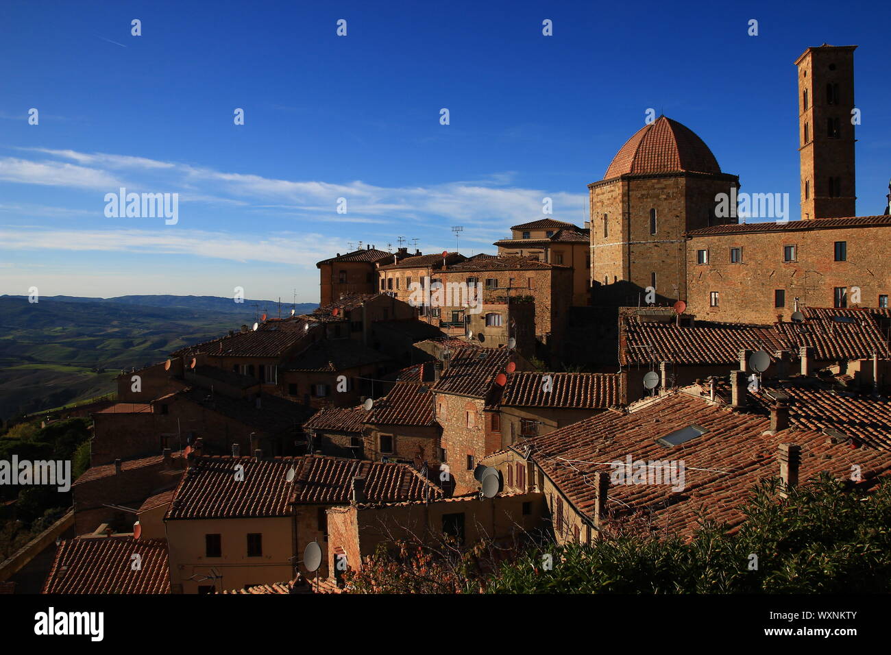 The roofs of the medieval town of Volterra overlook the autumn hills of Tuscany. Satellite dishes, medieval architecture and rustic tiles: epochs mix. Stock Photo