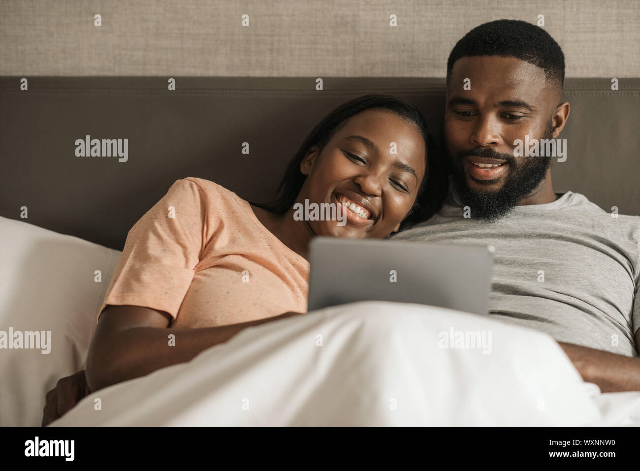 Young African American couple using a digital tablet in bed Stock Photo