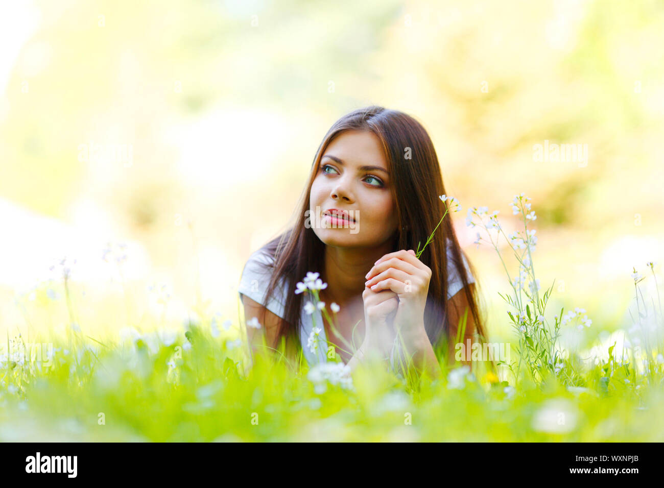 Beautiful young woman lying on grass with flowers Stock Photo - Alamy