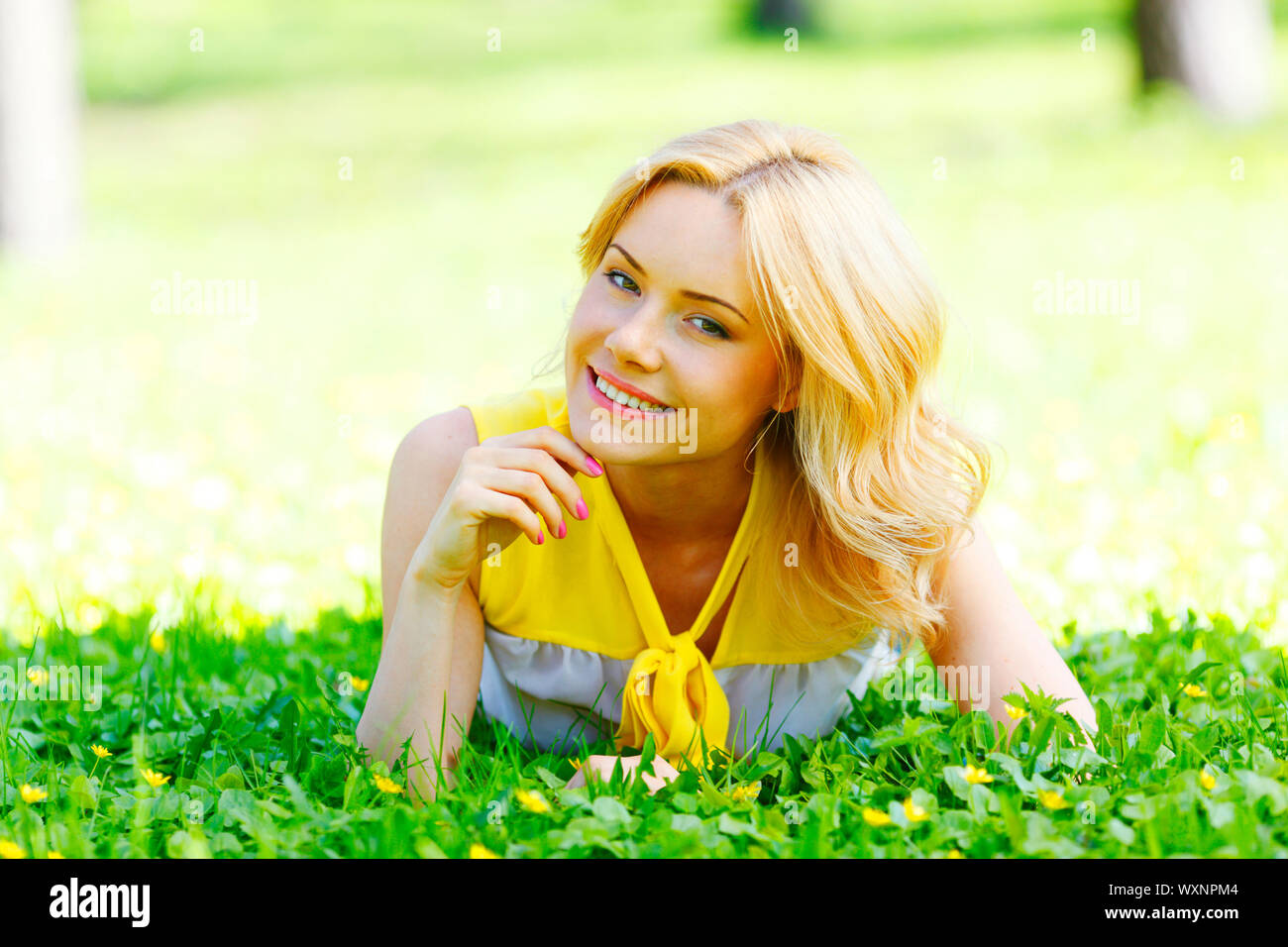 Happy young woman lying on grass Stock Photo - Alamy