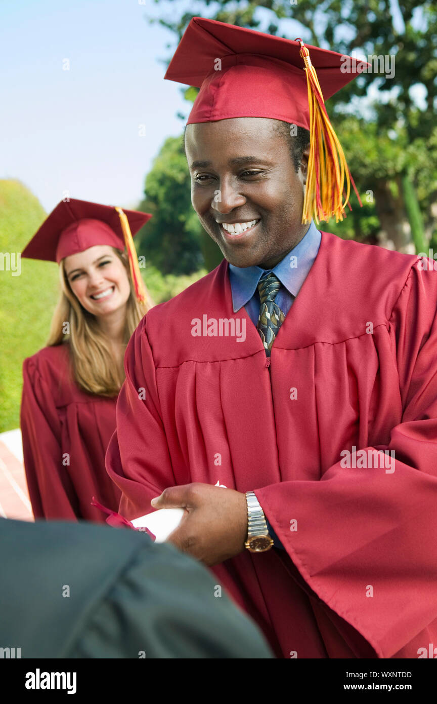 Graduate Shaking Hand and Receiving Diploma Stock Photo