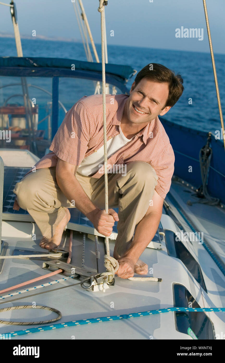 Man on Sailboat Tying Rope Stock Photo - Alamy