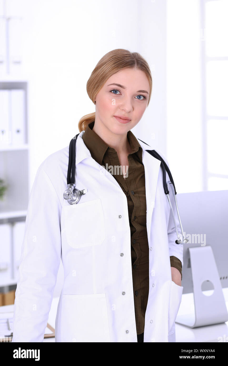 Young woman doctor at work in hospital looking at desktop pc monitor ...