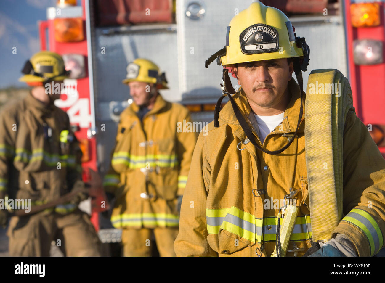 Portrait of firefighter carrying hose Stock Photo - Alamy