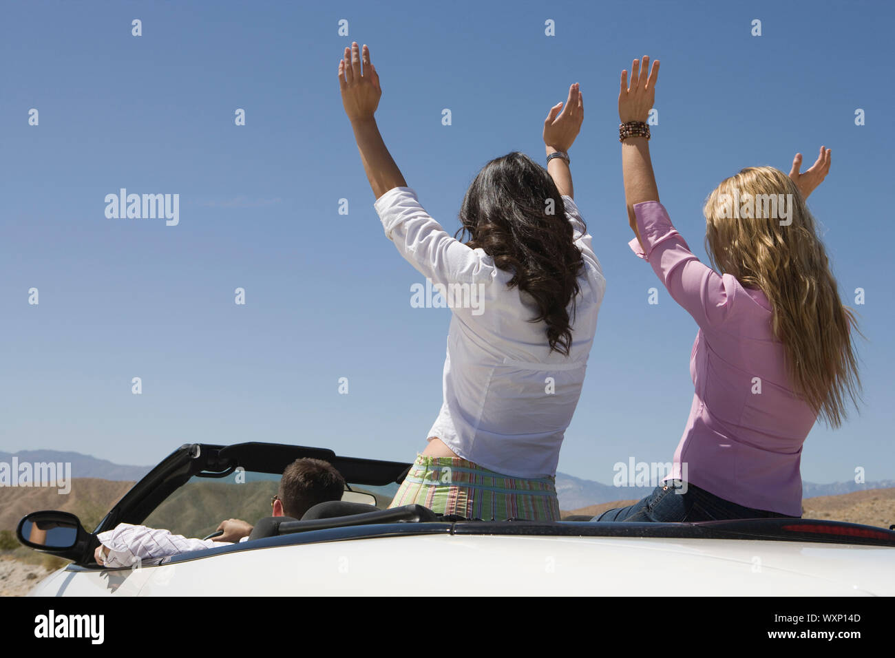 Man and two young women raising arms in car Stock Photo - Alamy