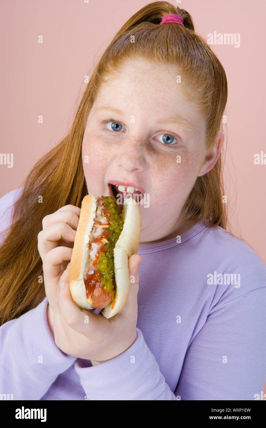 Overweight girl eating hot dog, portrait Stock Photo