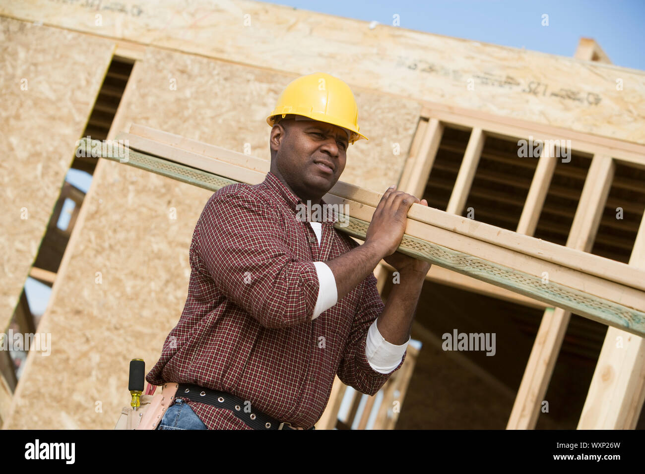 Construction worker carrying wooden plank Stock Photo - Alamy
