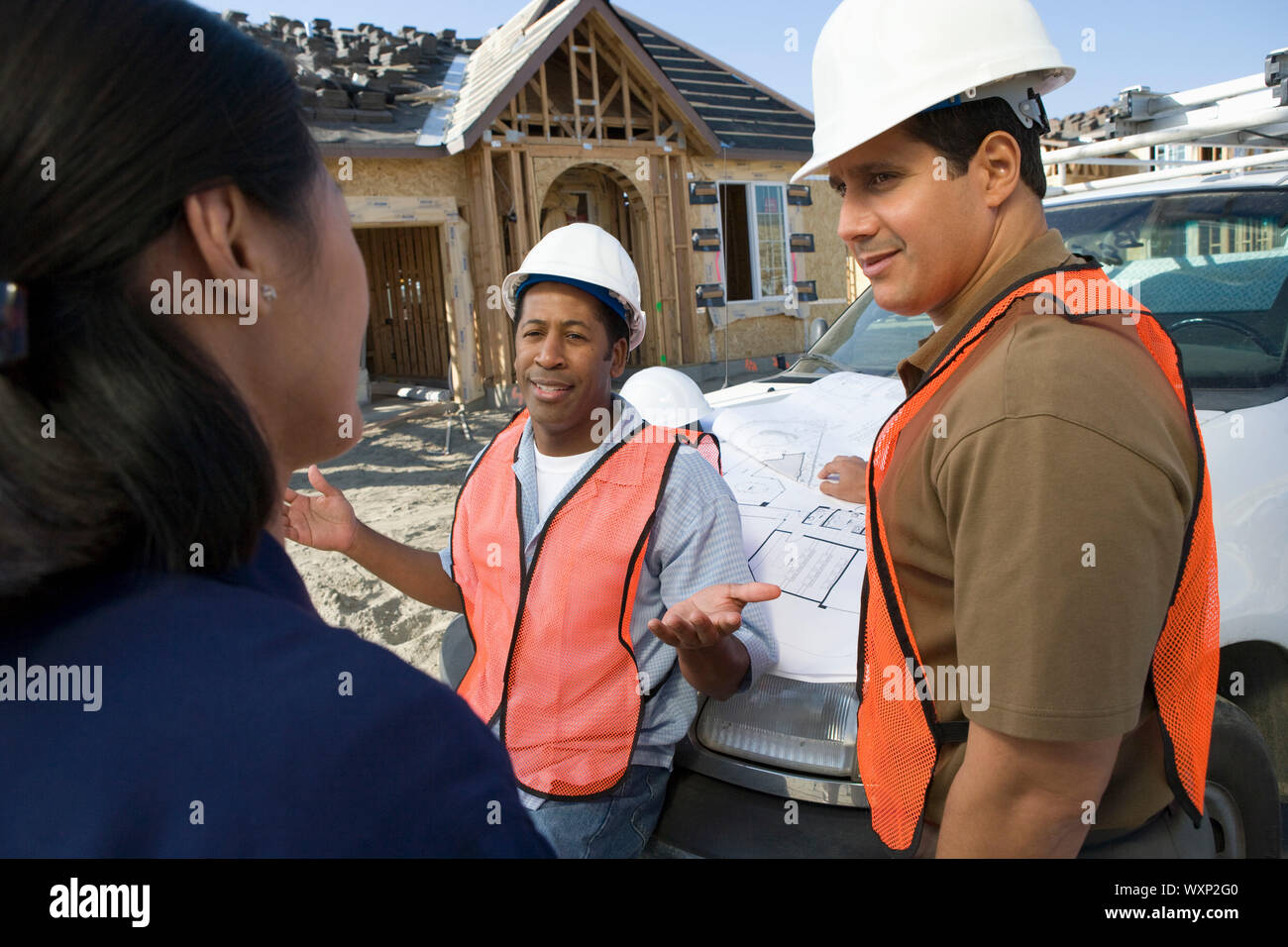 Architect and two construction workers having discussion on construction site Stock Photo