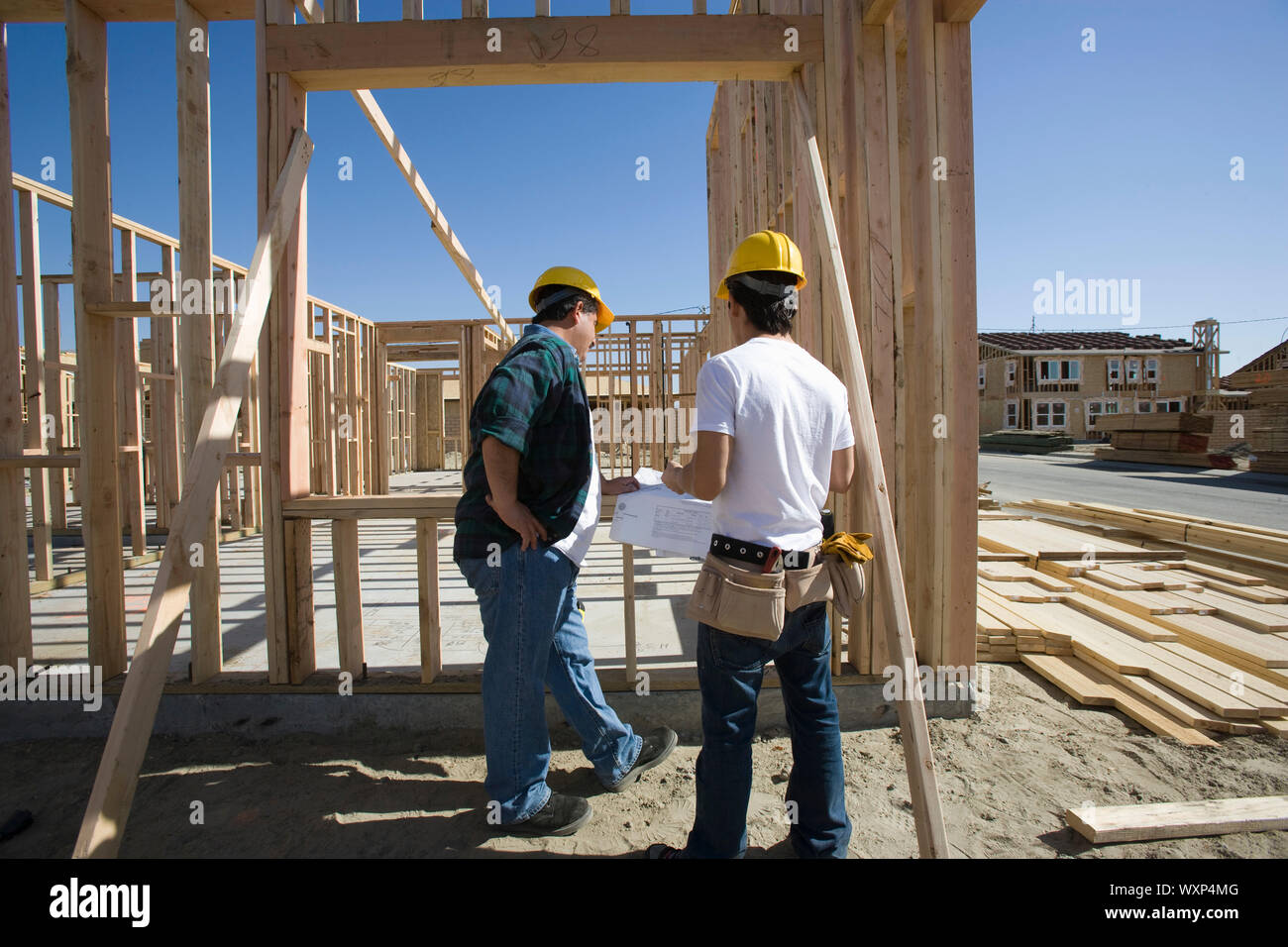 Construction workers reading blueprint on building site Stock Photo Alamy